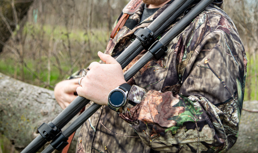 Hunter carrying a folded KJI shooting tripod through the field
